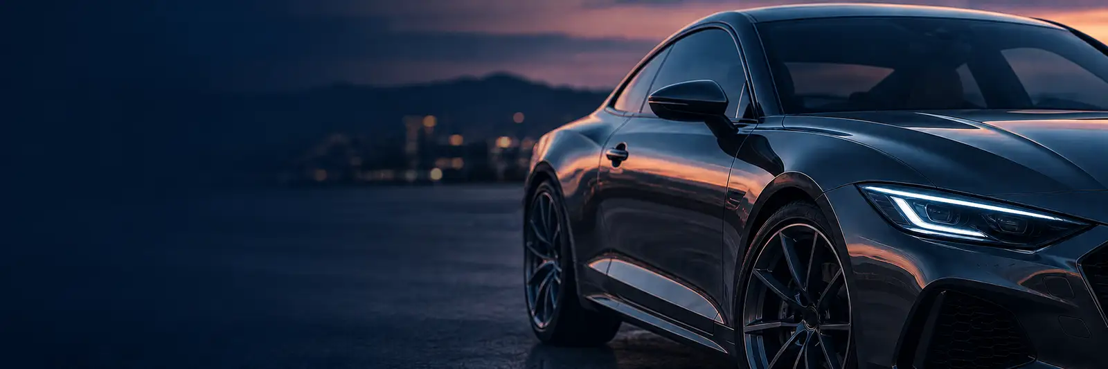 Coupé gris oscuro al atardecer con la ciudad al fondo